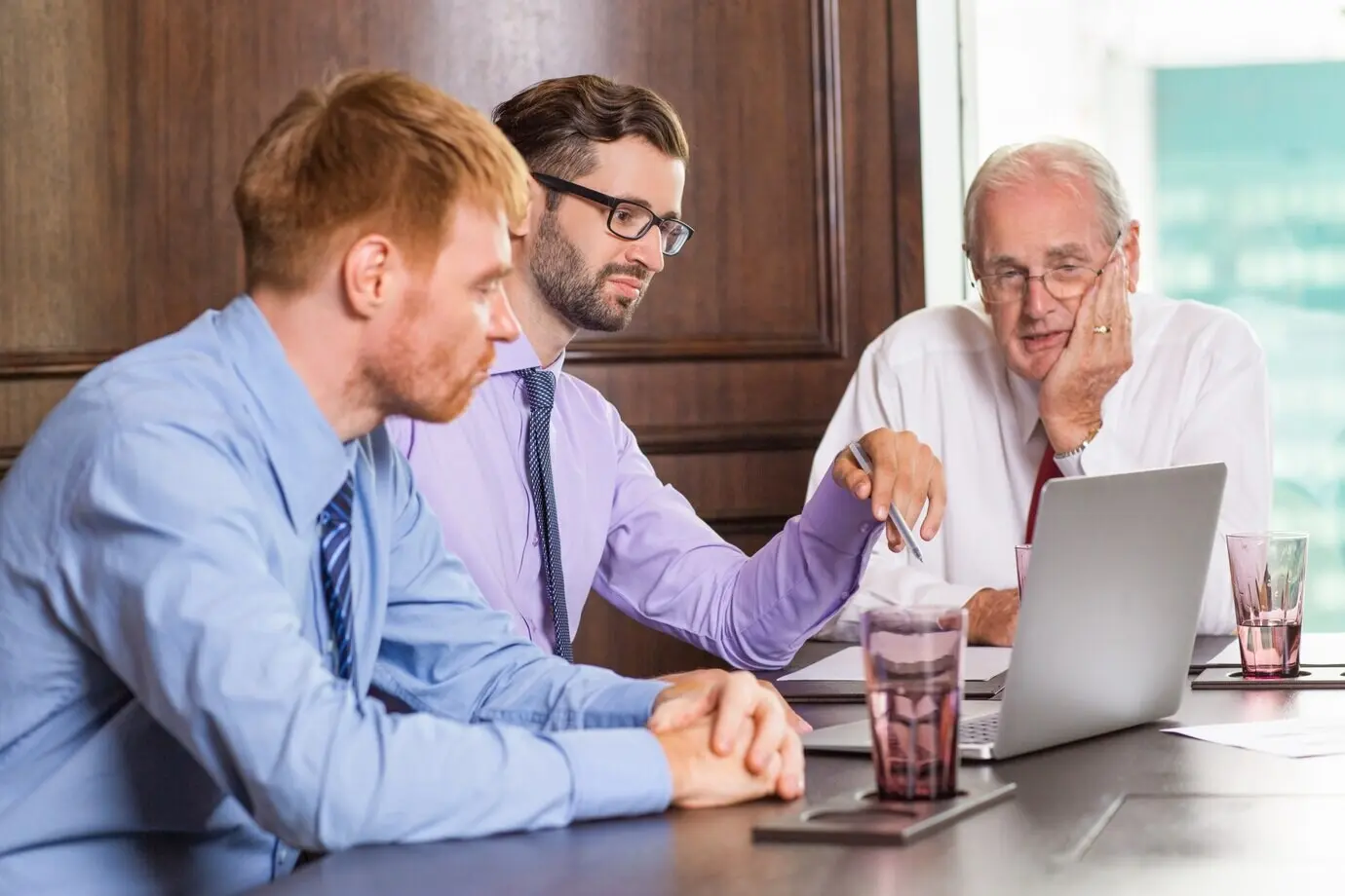 Hombre de negocios sénior mirando el portátil de otro empleado.